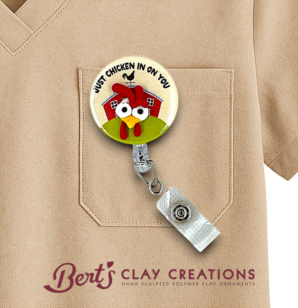 Retractable badge holder with cartoon chicken design on a beige shirt, featuring 'Bert's Clay Creations' branding.