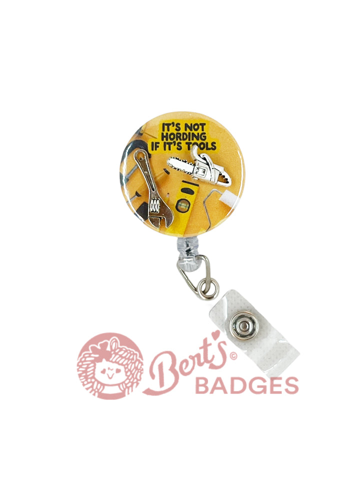 A retractable badge reel with a yellow reel charm featuring a wrench and the text 'It's not hoarding if it's tools' on a white background.