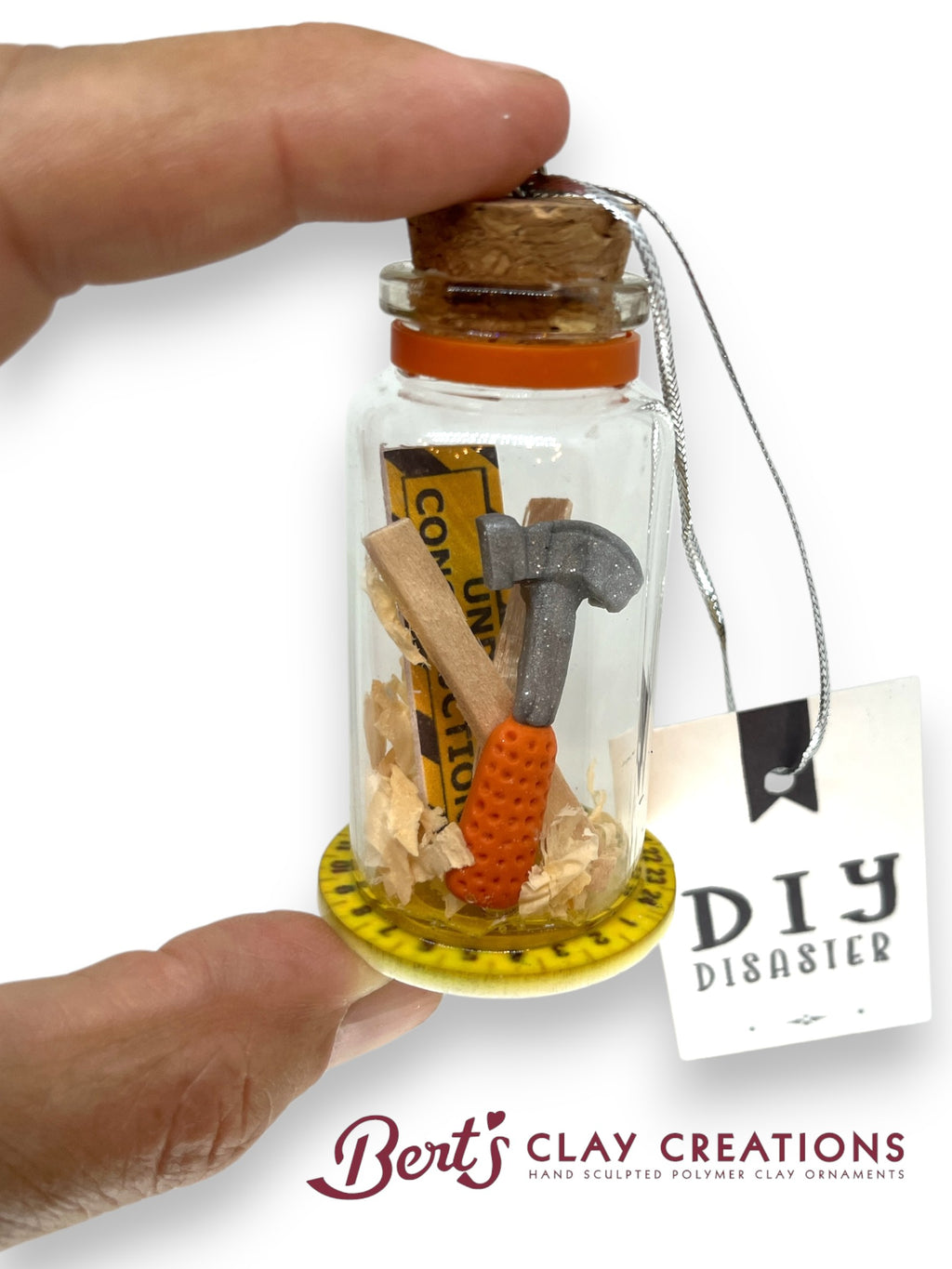 Small bottle with miniature tools and a 'DIY Disaster' tag, held by a hand.