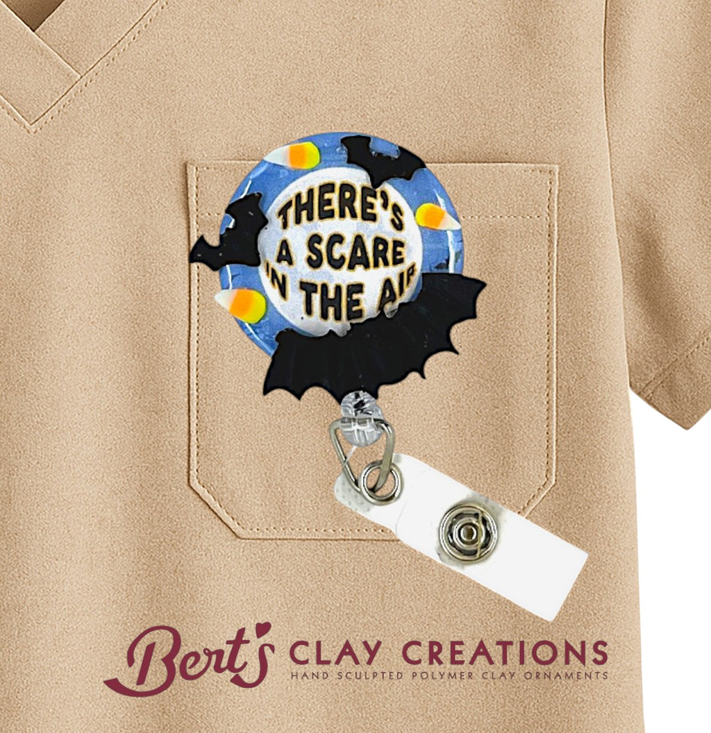 Halloween-themed badge holder with 'There's a Scare in the Air' text on a beige shirt, featuring the brand 'Bert's Clay Creations'.