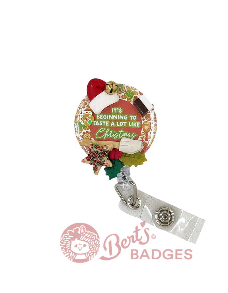 A festive badge reel topper with a clay Santa hat, Christmas cookies, and decorations against a holiday-themed background.