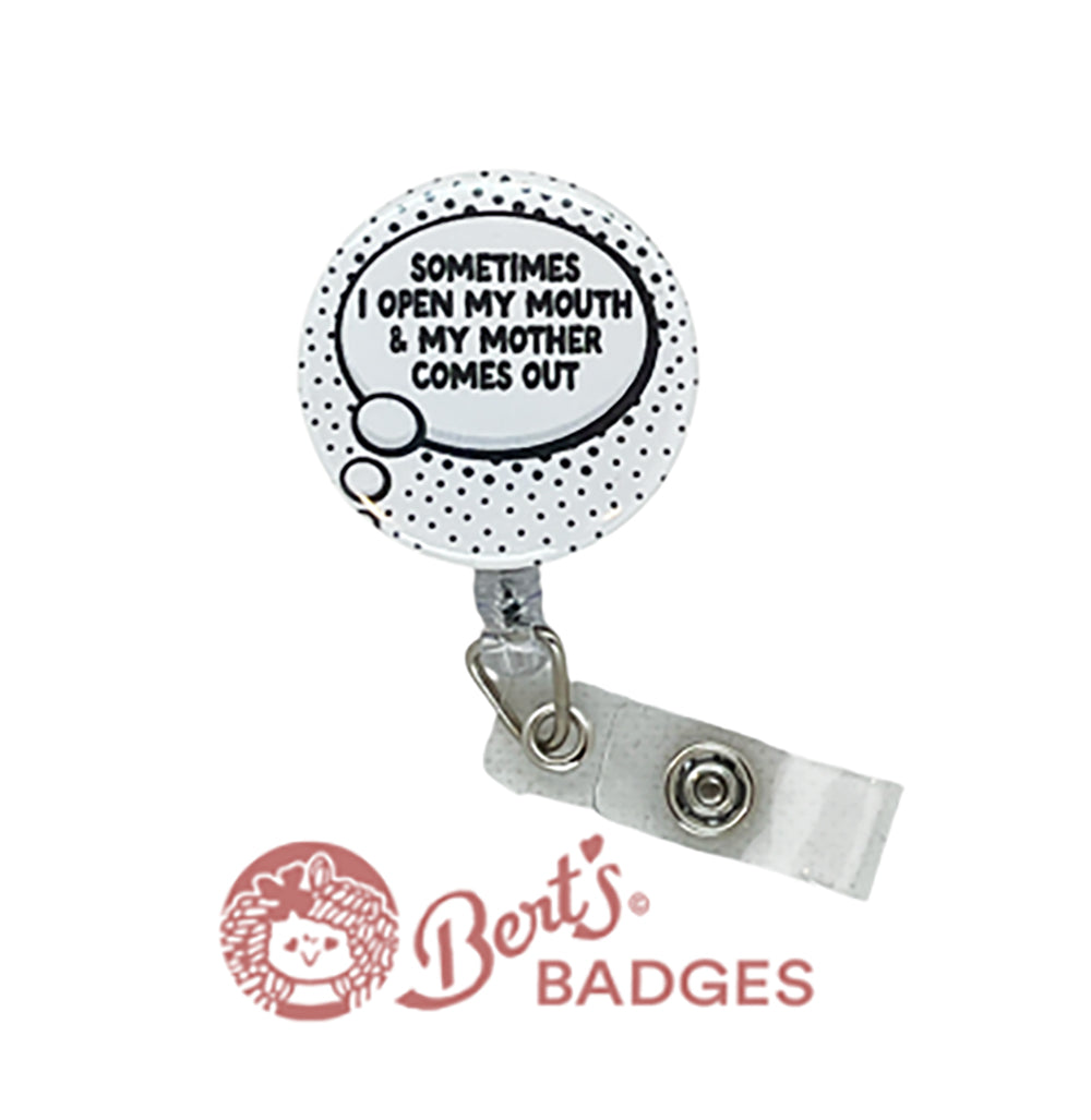 A black and white badge reel with a humorous quote attached to a clear badge holder, featuring a small decorative clay charm.
