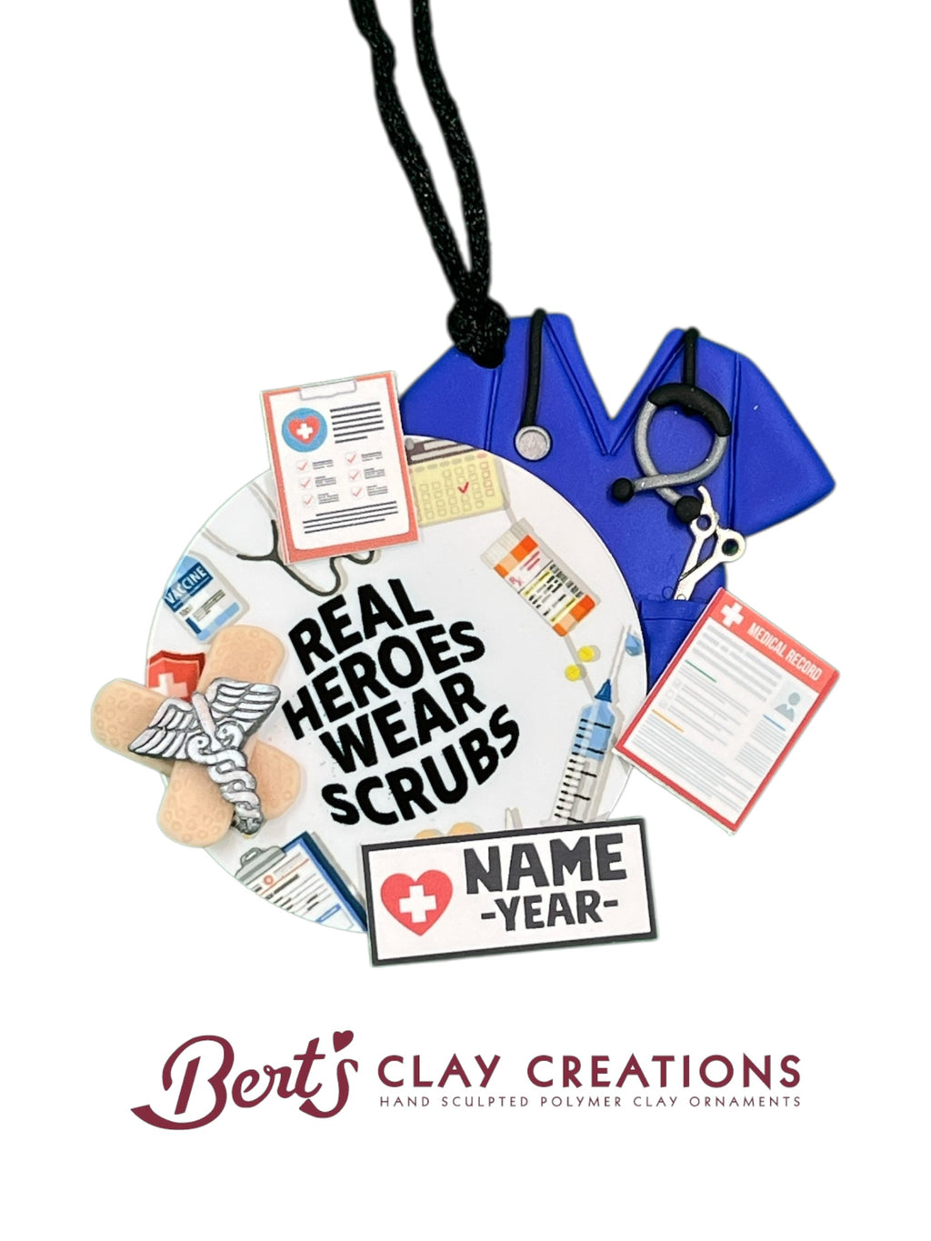 • Hand-sculpted polymer clay ornament for healthcare workers
• Miniature medical-themed decorations including scrubs, stethoscope, and clipboard
• Text reads “REAL HEROES WEAR SCRUBS” with customizable nameplate
• Ornament with black hanging string and circular base
• Gift-ready packaging from Bert’s Clay Creations
• Personalized holiday ornament for nurse, doctor, or EMT