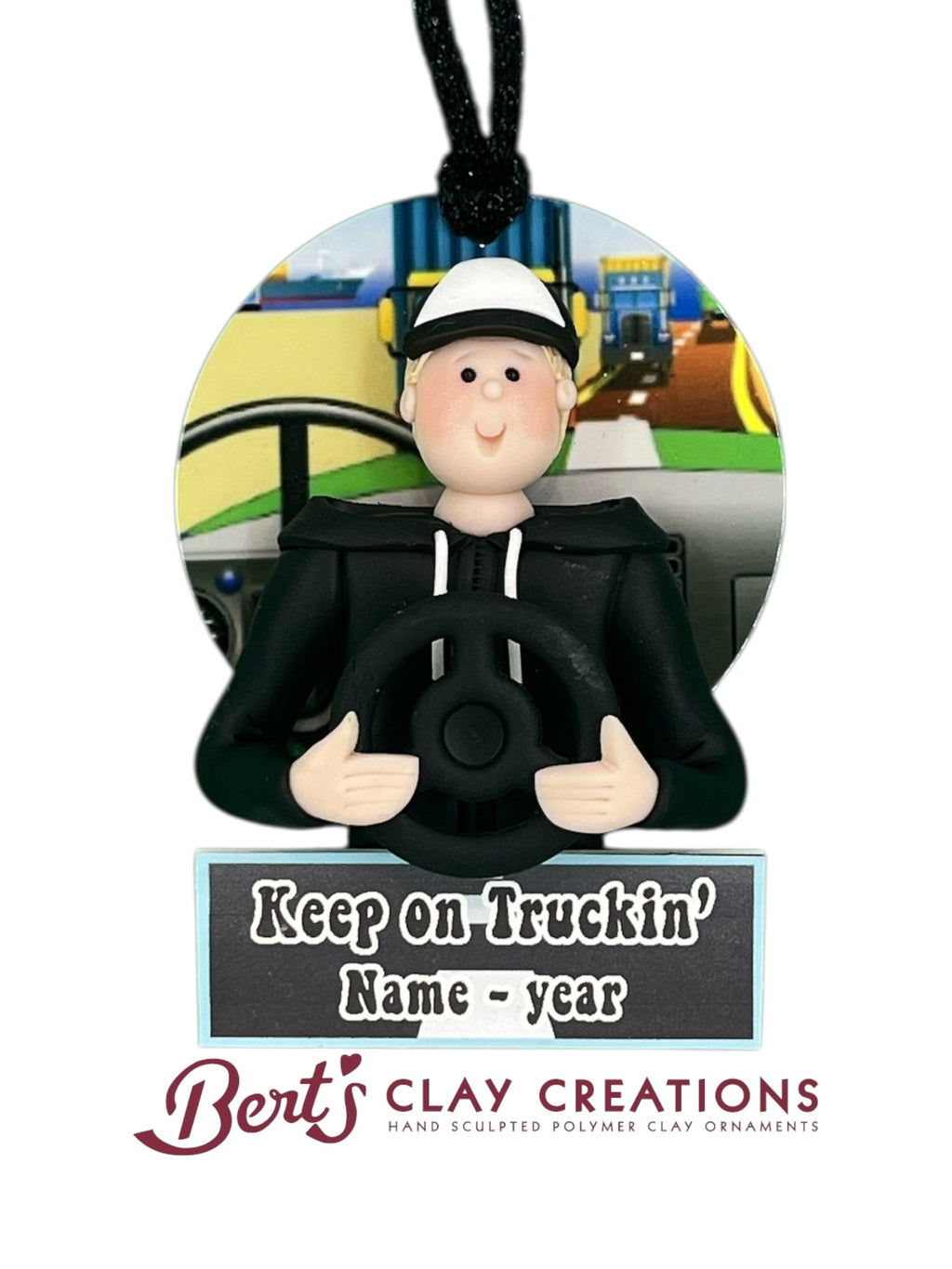 Hand-sculpted polymer clay ornament featuring a truck driver in a cab with a scenic road view, holding a steering wheel. Includes a customizable nameplate reading “Keep on Truckin’ Name - year.” Designed by Bert’s Clay Creations.