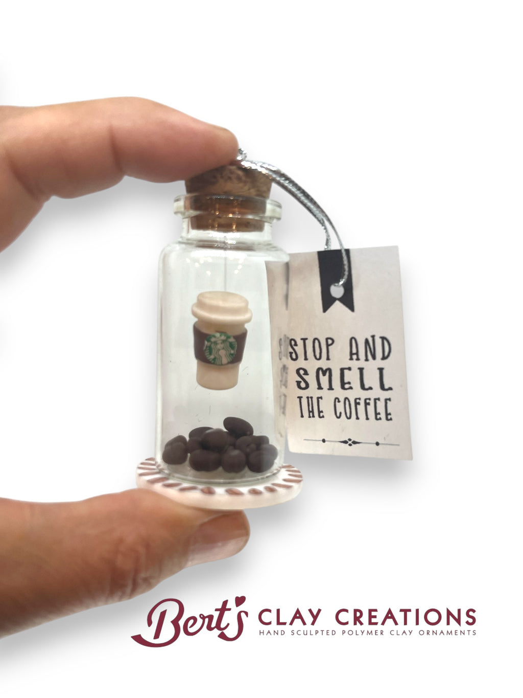 Glass bottle with coffee-themed contents and 'Stop and Smell the Coffee' tag, held by a hand.