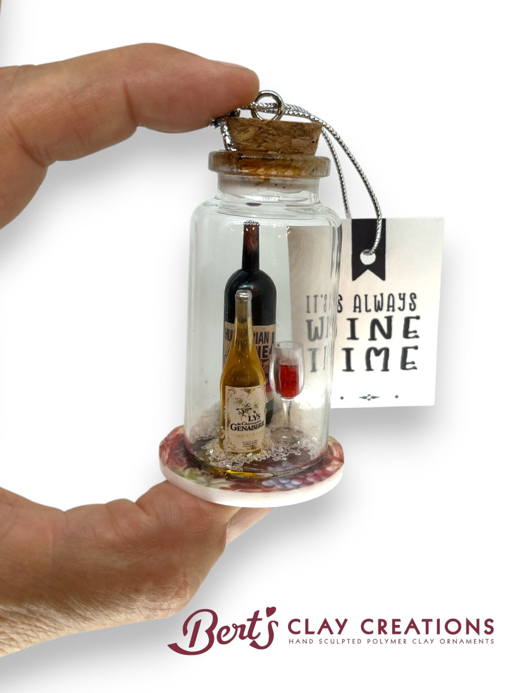 Decorative glass jar with miniature bottles and a cork lid, held by a hand. 'It's Always Wine Time' tag visible.