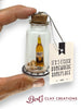 Miniature bottle with a Corona beer bottle inside, held by a hand, with a tag reading 'It's 5 o'clock somewhere someplace' by Berts Clay Creations.