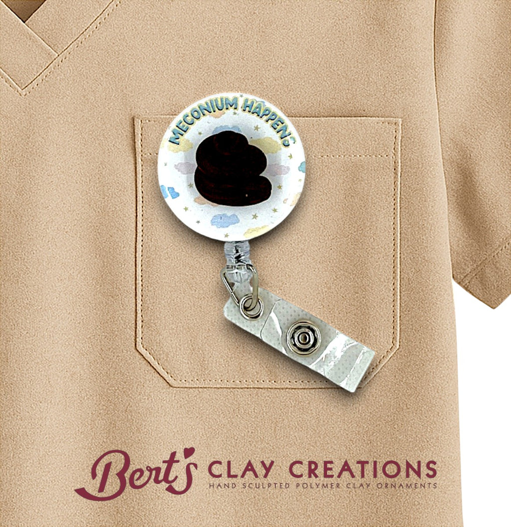 Retractable badge holder with 'Meconium Happens' design on a beige shirt, featuring Bert's Clay Creations branding.