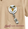 Badge holder with bee design attached to a beige shirt, featuring 'Bert's Clay Creations' logo.