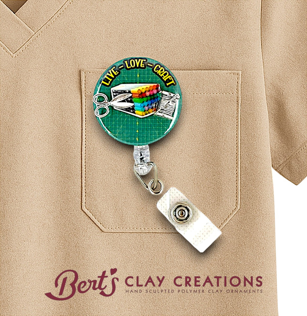 Retractable badge holder with colorful design on a beige shirt, featuring 'Bert's Clay Creations' branding.