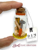 Small bottle with miniature tools and a 'DIY Disaster' tag, held by a hand.