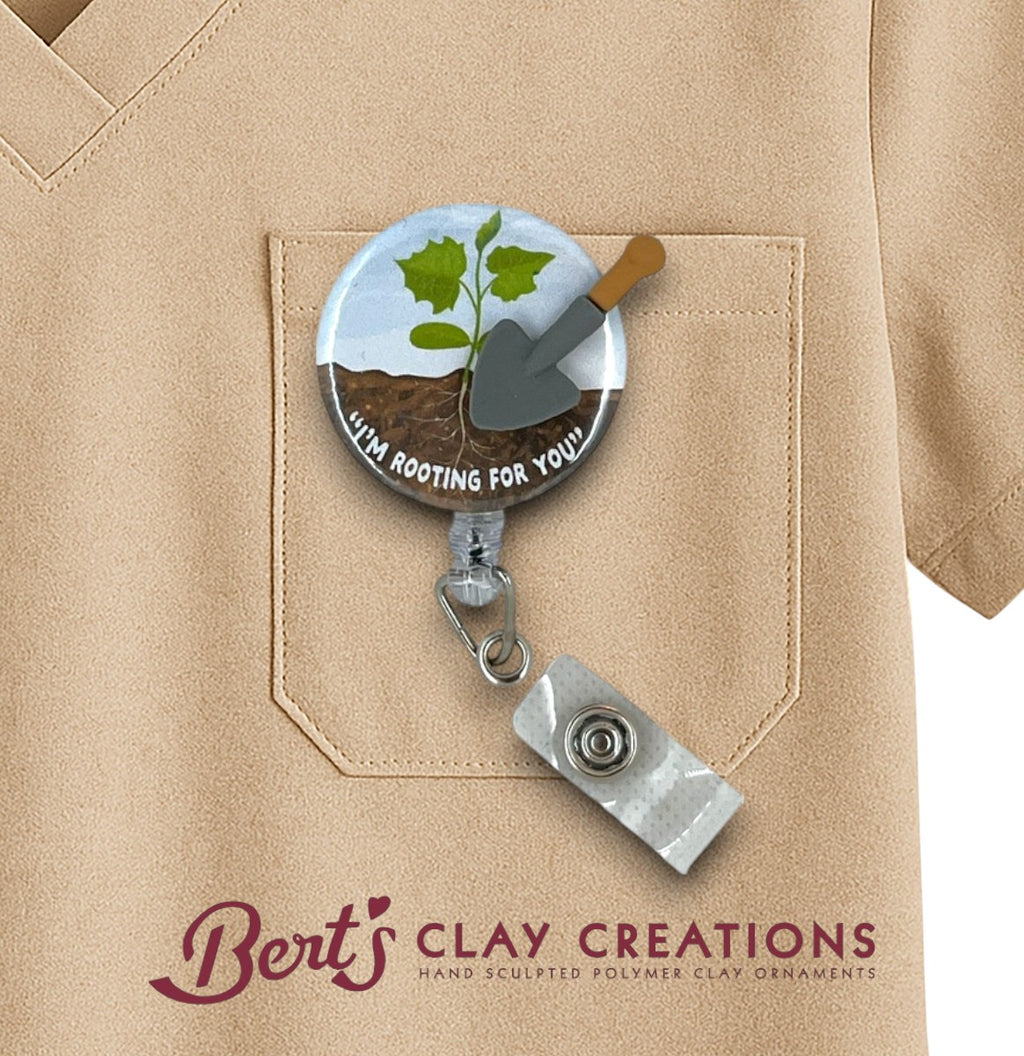 Badge holder with a plant design and 'Bert's Clay Creations' branding on a beige shirt.