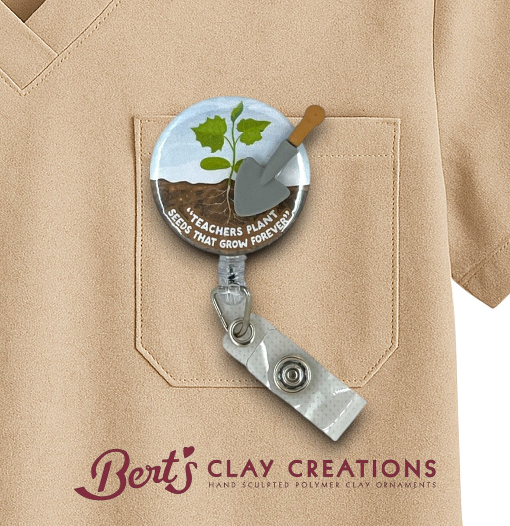 Teacher Interchangeable Badge holder with a plant and shovel design on a beige shirt, featuring 'Bert's Clay Creations' branding.