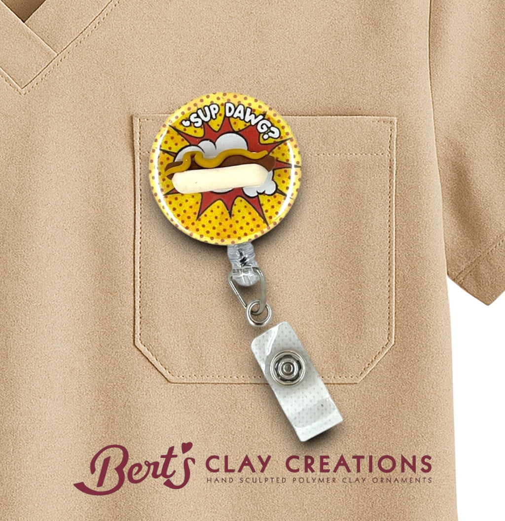 Badge holder with a cartoon design attached to a beige shirt, featuring 'Bert's Clay Creations' branding.