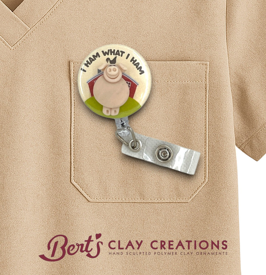 Badge holder with cartoon pig design on a beige shirt, featuring 'Bert's Clay Creations' branding.