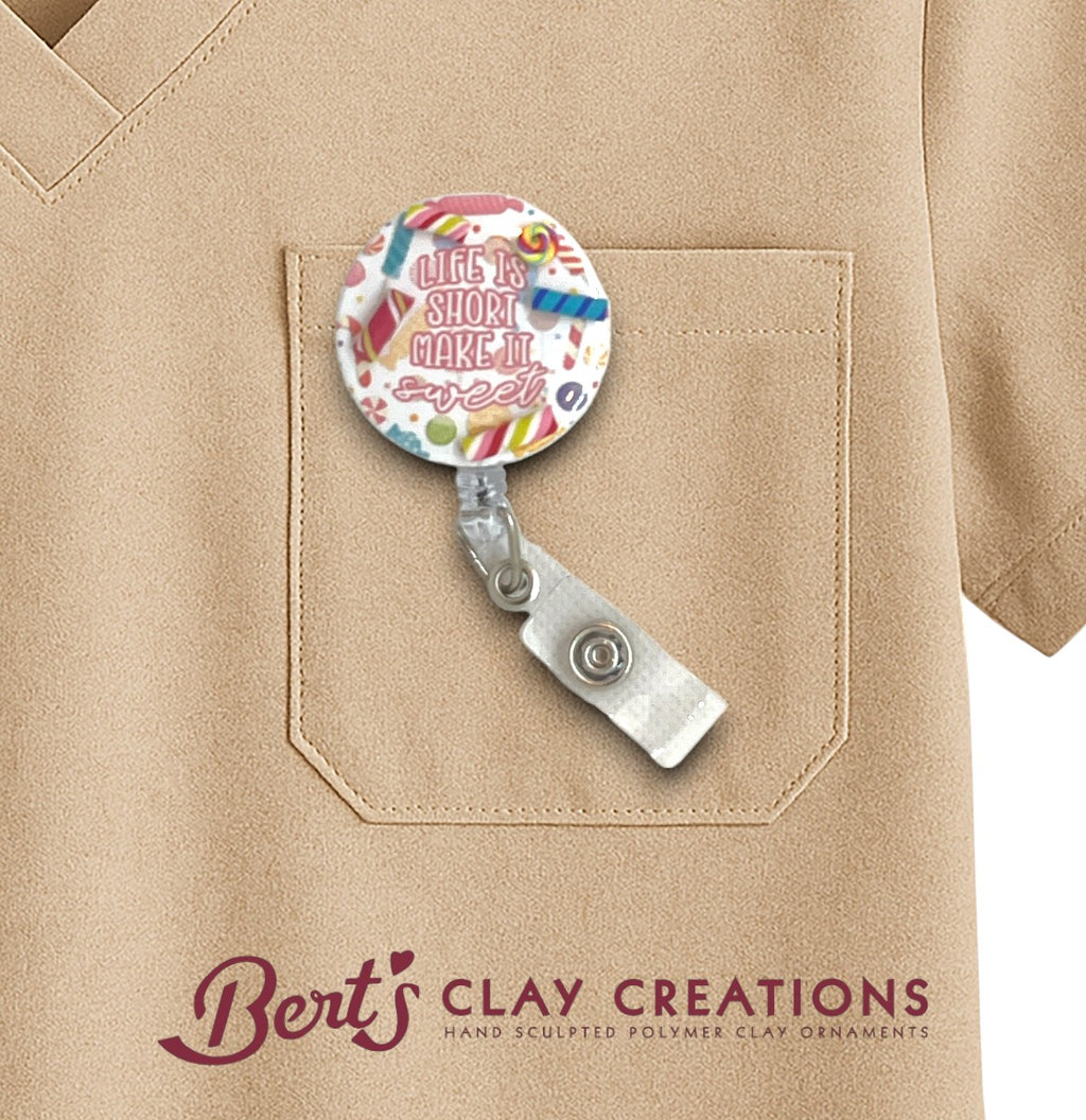 Retractable badge holder with colorful design on a beige shirt, featuring 'Bert's Clay Creations' branding.