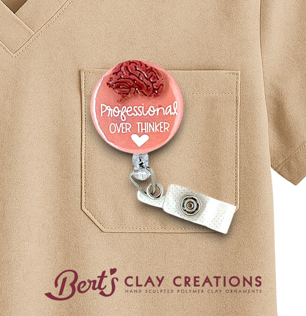 Pink badge holder with 'Professional Over Thinker' text on a beige shirt, featuring 'Bert's Clay Creations' branding.