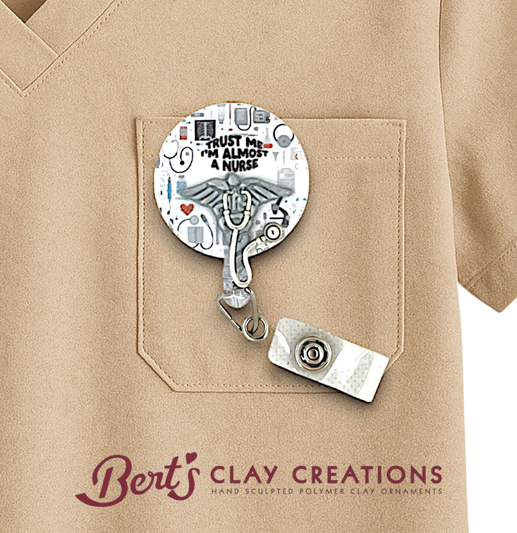 Medical School themed for doctor or nurse Retractable badge holder with artistic design on a beige shirt, featuring 'Bert's Clay Creations' branding.