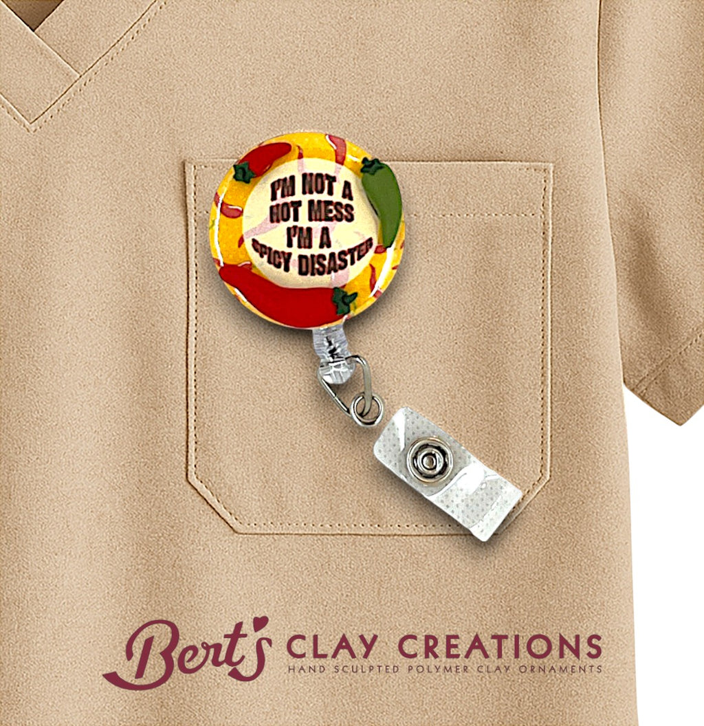 Colorful badge holder with humorous design attached to a beige shirt, featuring 'Bert's Clay Creations' branding.