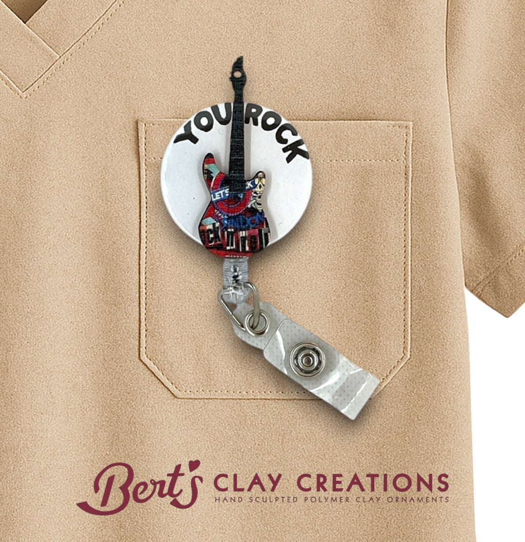 Guitar-shaped badge holder with 'You Rock' text on a beige shirt, featuring Bert's Clay Creations logo.