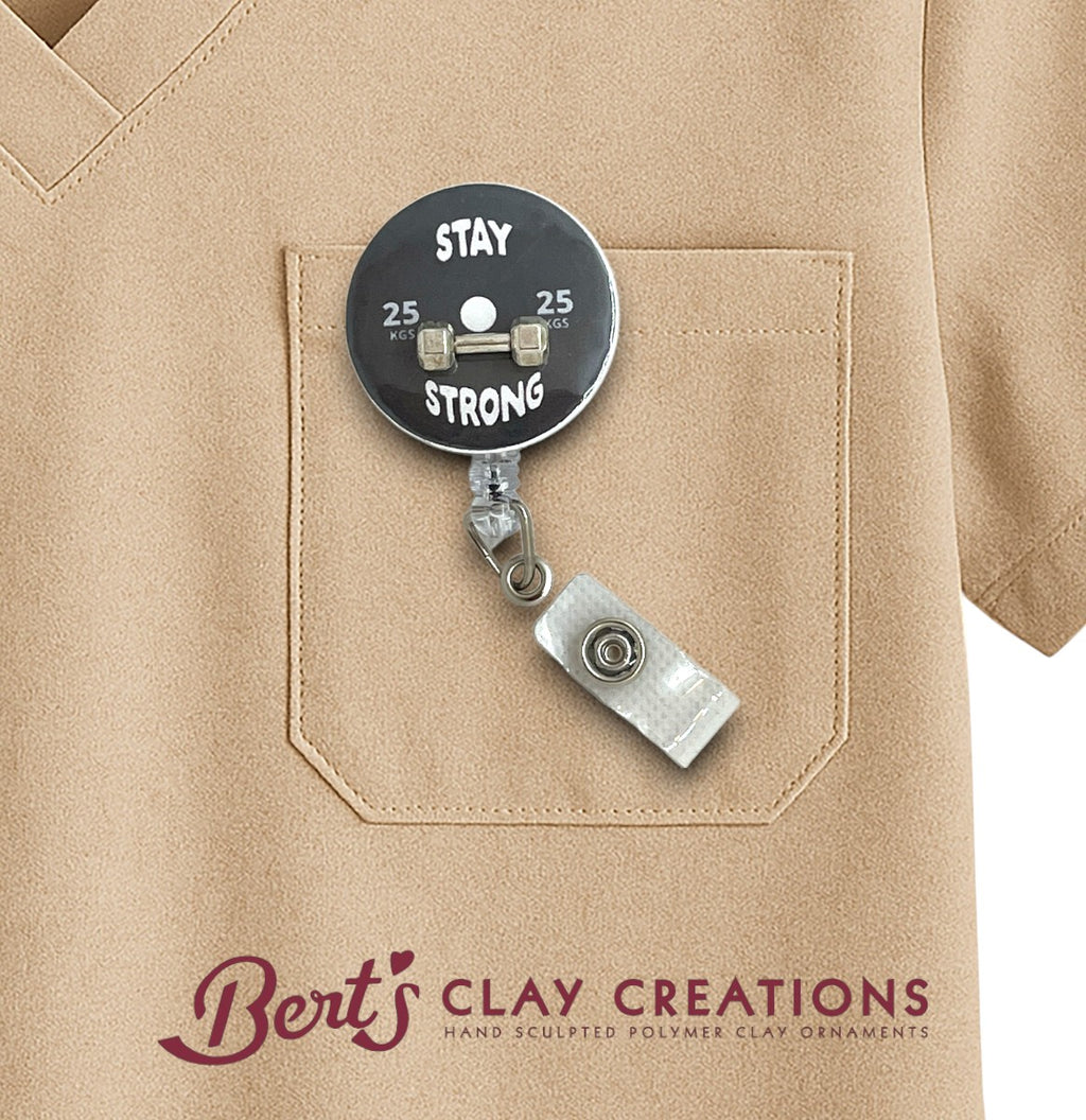 Retractable badge holder with 'Stay Strong' text on a beige shirt, featuring Bert's Clay Creations branding.