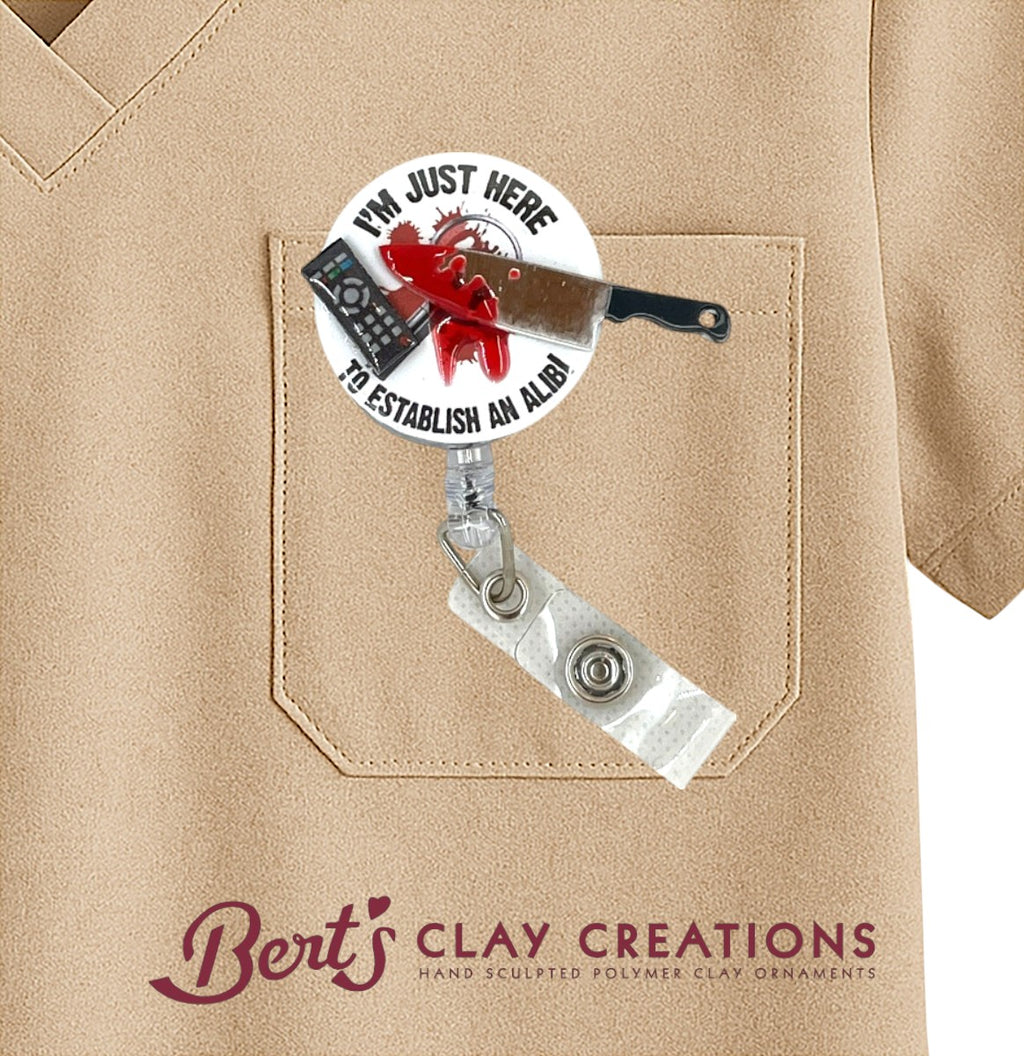 Badge holder with humorous design on a tan shirt, featuring 'Bert's Clay Creations' branding.