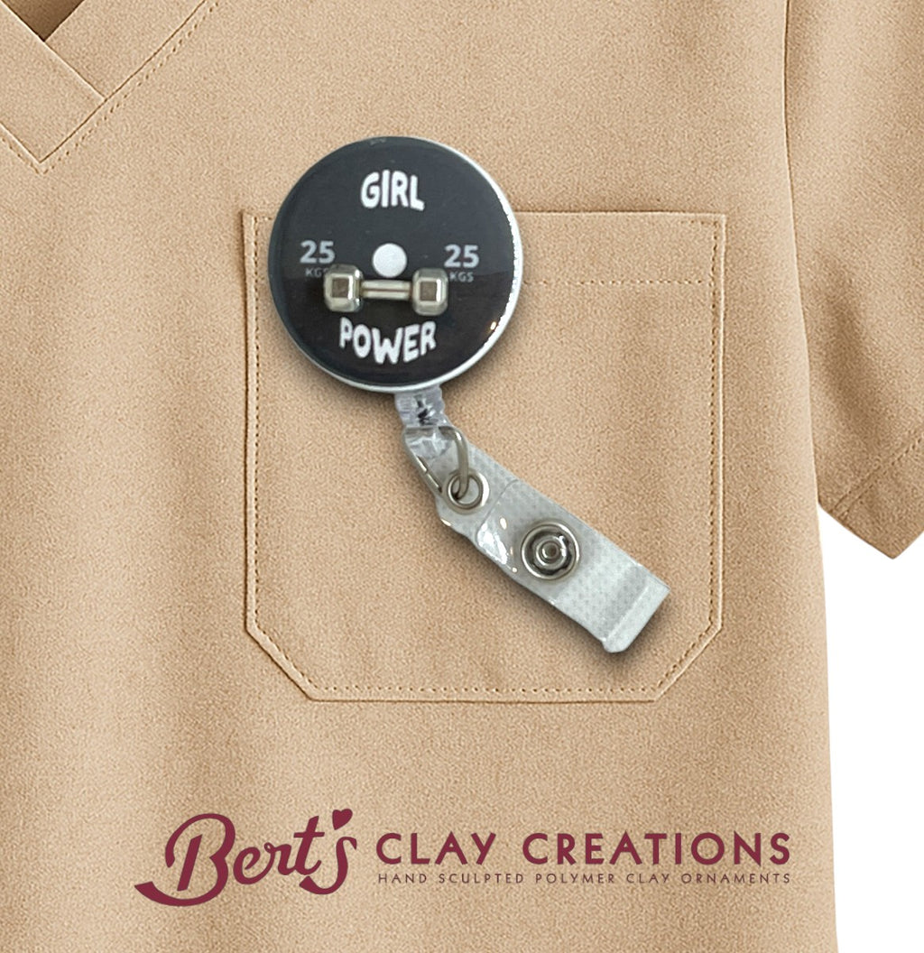 Badge holder with 'Girl Power' text on a beige shirt, featuring 'Bert's Clay Creations' branding.