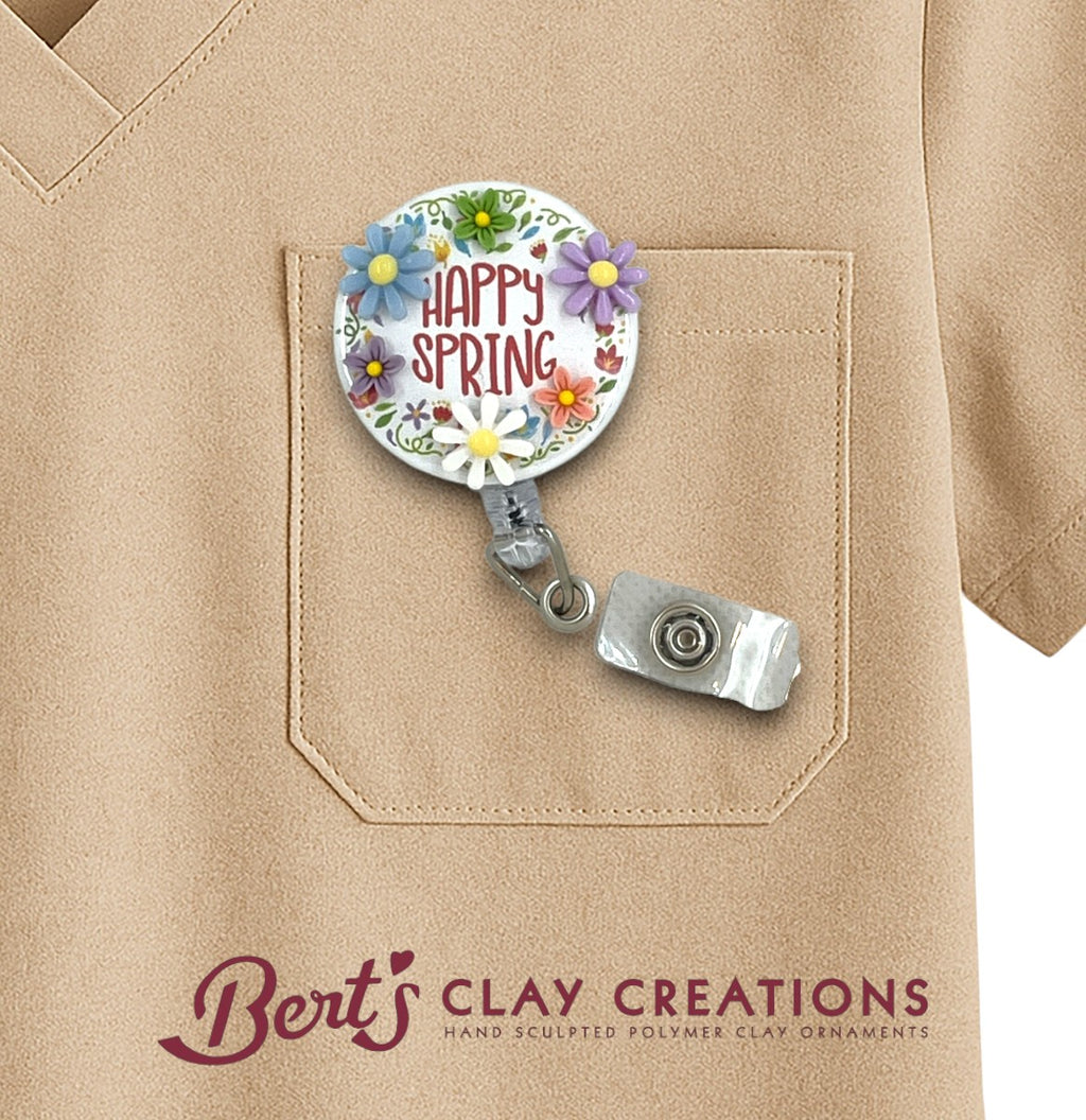 Retractable badge holder with floral design and 'Happy Spring' text on a beige shirt, featuring Bert's Clay Creations branding.