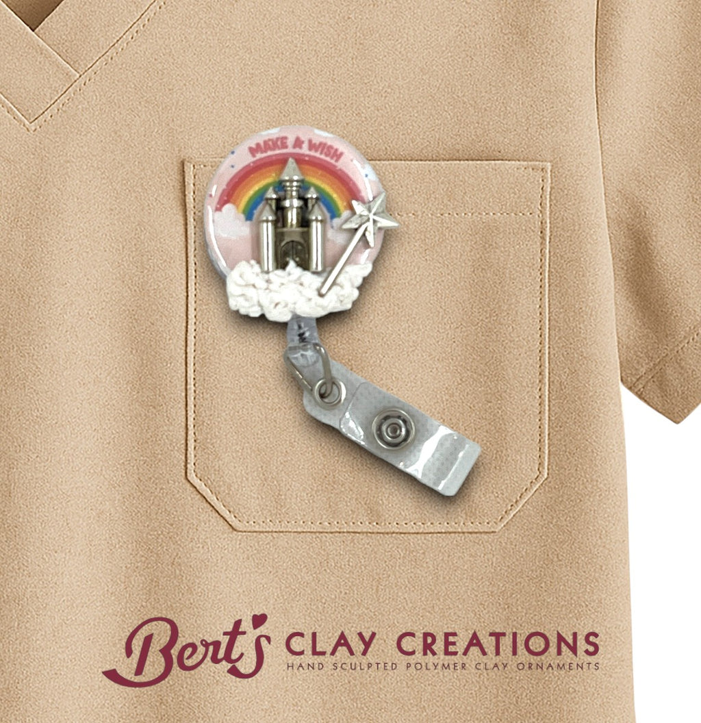 Badge holder with rainbow and castle design on a beige shirt, featuring 'Bert's Clay Creations' branding.
