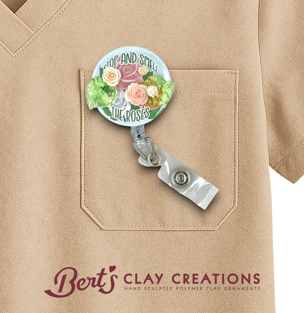 Floral-themed badge holder on a beige shirt with 'Bert's Clay Creations' branding.